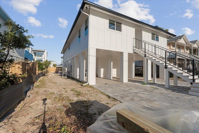 rear view of house with fence, board and batten siding, stairs, and a patio area