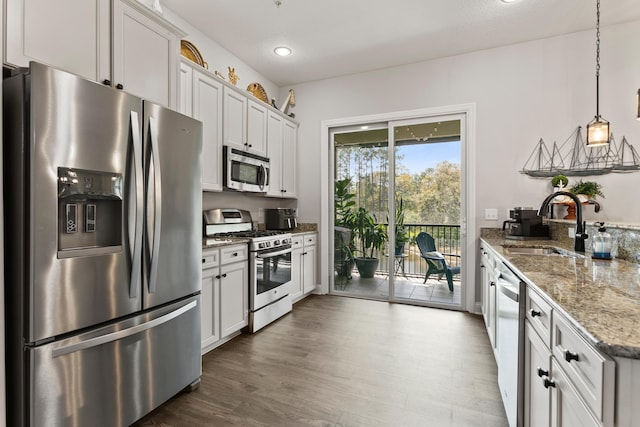121 Grand Ravine Dr, Saint Augustine, FL 32086 - kitchen featuring stainless steel appliances, a sink, light stone counters, dark wood finished floors, and pendant lighting