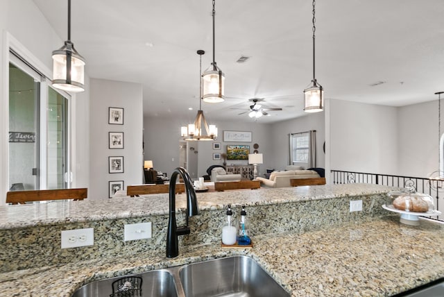 121 Grand Ravine Dr, Saint Augustine, FL 32086 - kitchen featuring a sink, a ceiling fan, a chandelier, open floor plan, and light stone counters