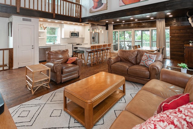 living room featuring a towering ceiling, light wood-type flooring, and a healthy amount of sunlight