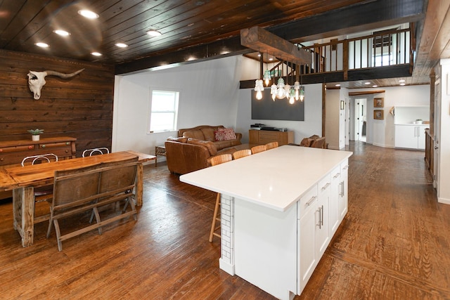 kitchen with white cabinets, hanging light fixtures, a center island, and dark wood-type flooring