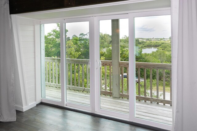 doorway to outside with dark hardwood / wood-style flooring and a water view