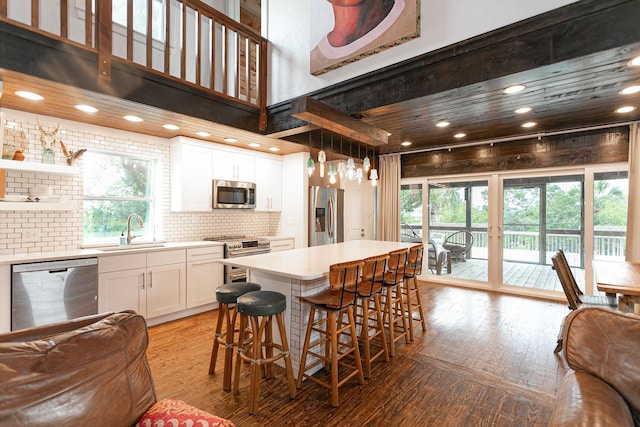 kitchen featuring light hardwood / wood-style flooring, a kitchen island, white cabinets, appliances with stainless steel finishes, and sink