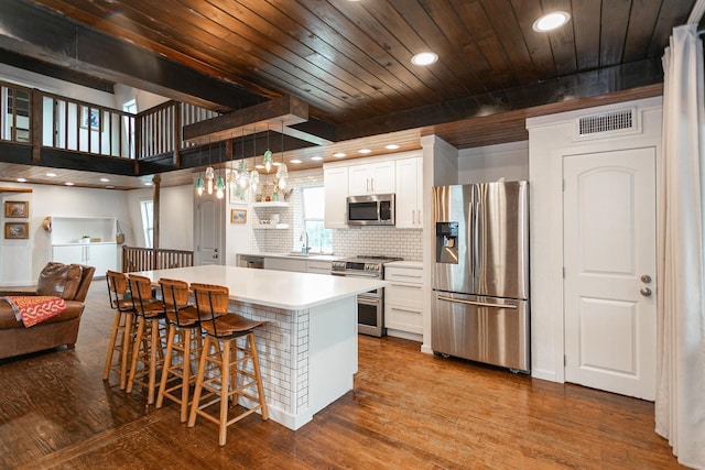 kitchen featuring pendant lighting, stainless steel appliances, a breakfast bar, white cabinetry, and sink