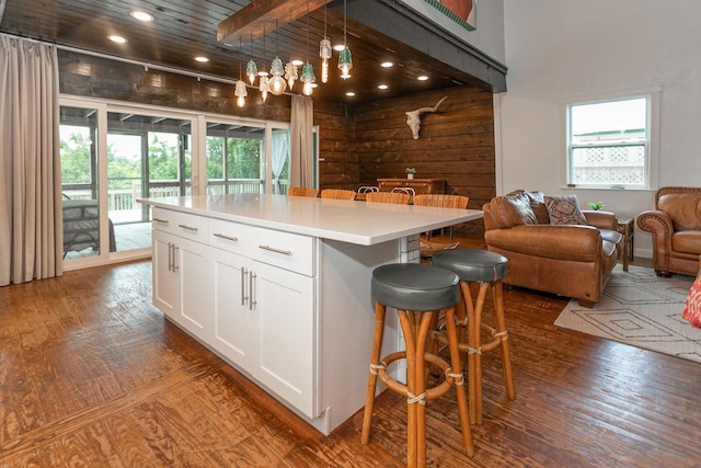 kitchen with a center island, decorative light fixtures, hardwood / wood-style floors, a breakfast bar area, and white cabinetry