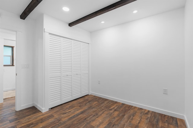 unfurnished bedroom with ceiling fan, beam ceiling, a closet, and dark hardwood / wood-style floors