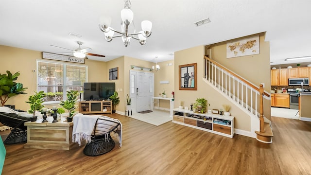 living room with ceiling fan with notable chandelier and light hardwood / wood-style flooring