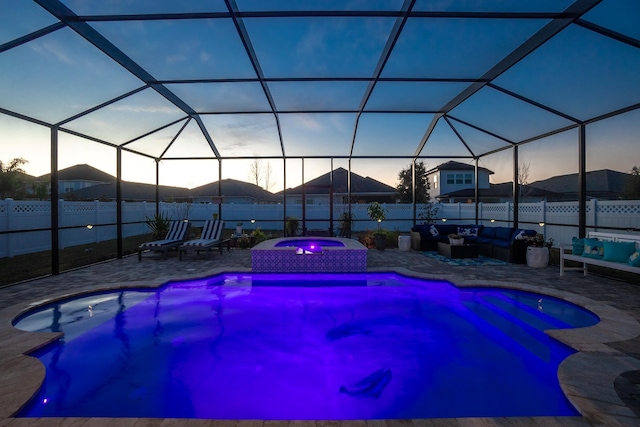 pool at dusk with glass enclosure, an in ground hot tub, a patio, a mountain view, and an outdoor living space