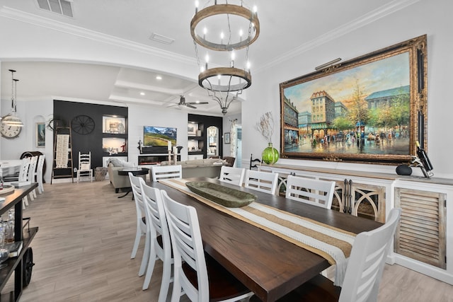 dining space featuring ceiling fan with notable chandelier, light hardwood / wood-style floors, and crown molding