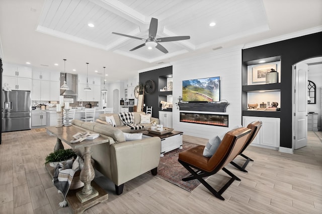 living room with ornamental molding, built in shelves, ceiling fan, and beam ceiling