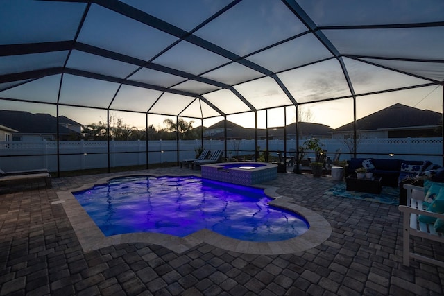 pool at dusk featuring an in ground hot tub, a lanai, and a patio area