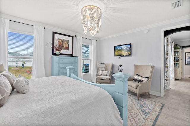 bedroom with light wood-type flooring, ornamental molding, and an inviting chandelier