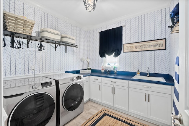 clothes washing area featuring sink, light wood-type flooring, ornamental molding, cabinets, and independent washer and dryer