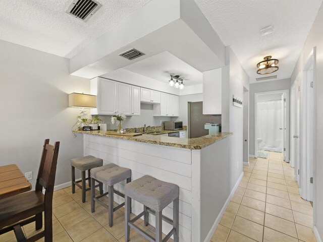 129 Rio Del Mar St Unit C, Saint Augustine, FL 32080 - kitchen with a textured ceiling, light tile patterned floors, stainless steel appliances, light stone countertops, and baseboards