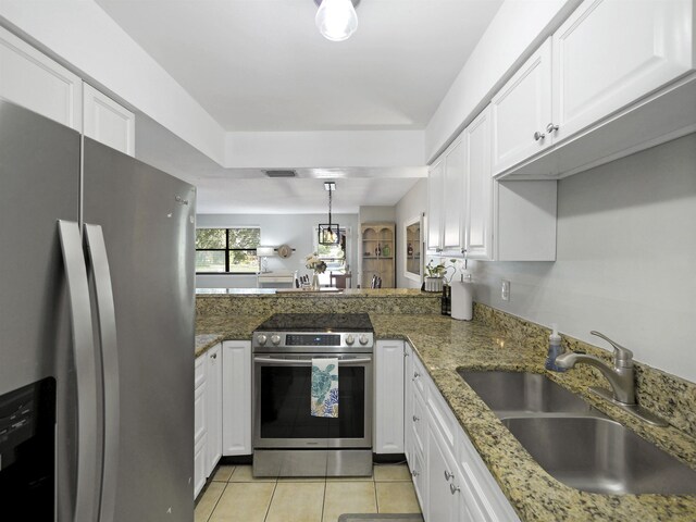 129 Rio Del Mar St Unit C, Saint Augustine, FL 32080 - kitchen featuring appliances with stainless steel finishes, a sink, light tile patterned floors, white cabinetry, and stone countertops