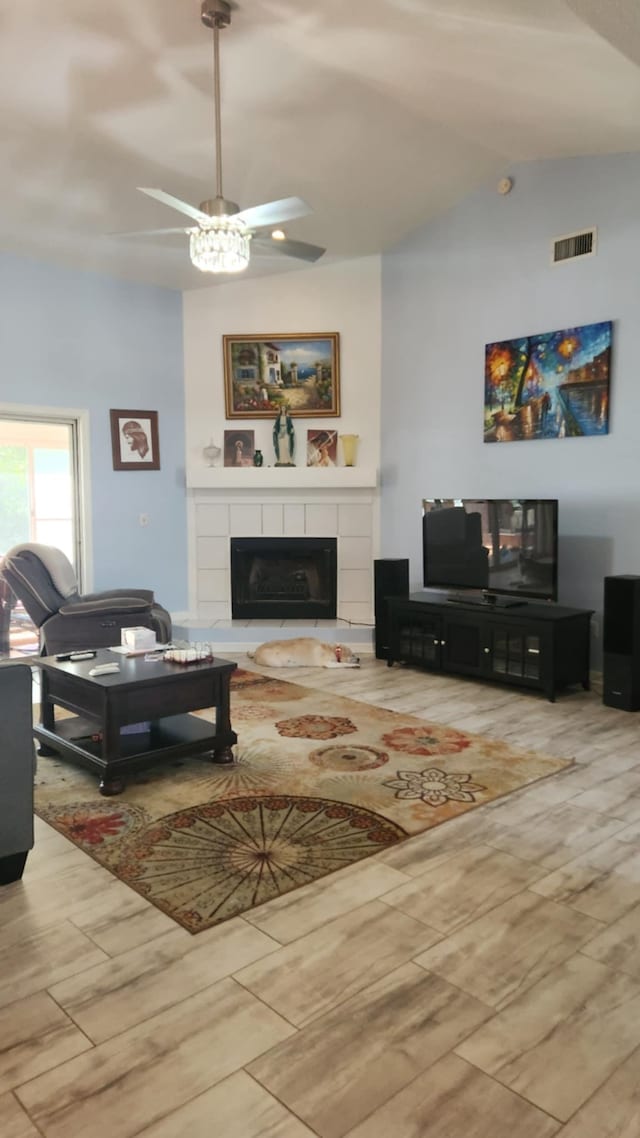 living room featuring visible vents, lofted ceiling, and a tile fireplace