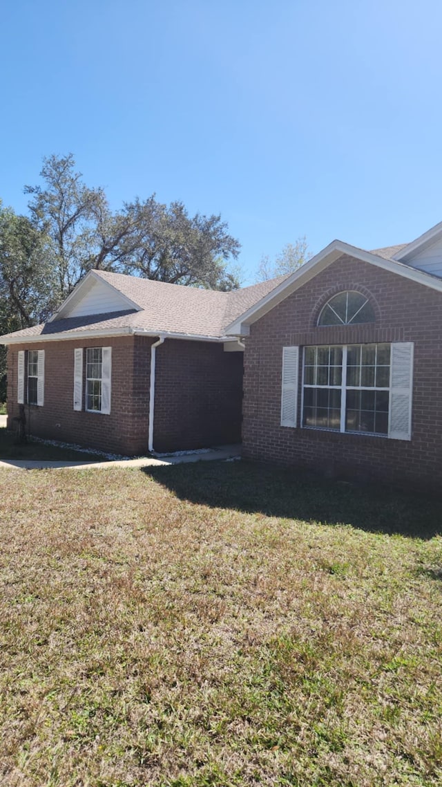 view of property exterior featuring brick siding and a lawn