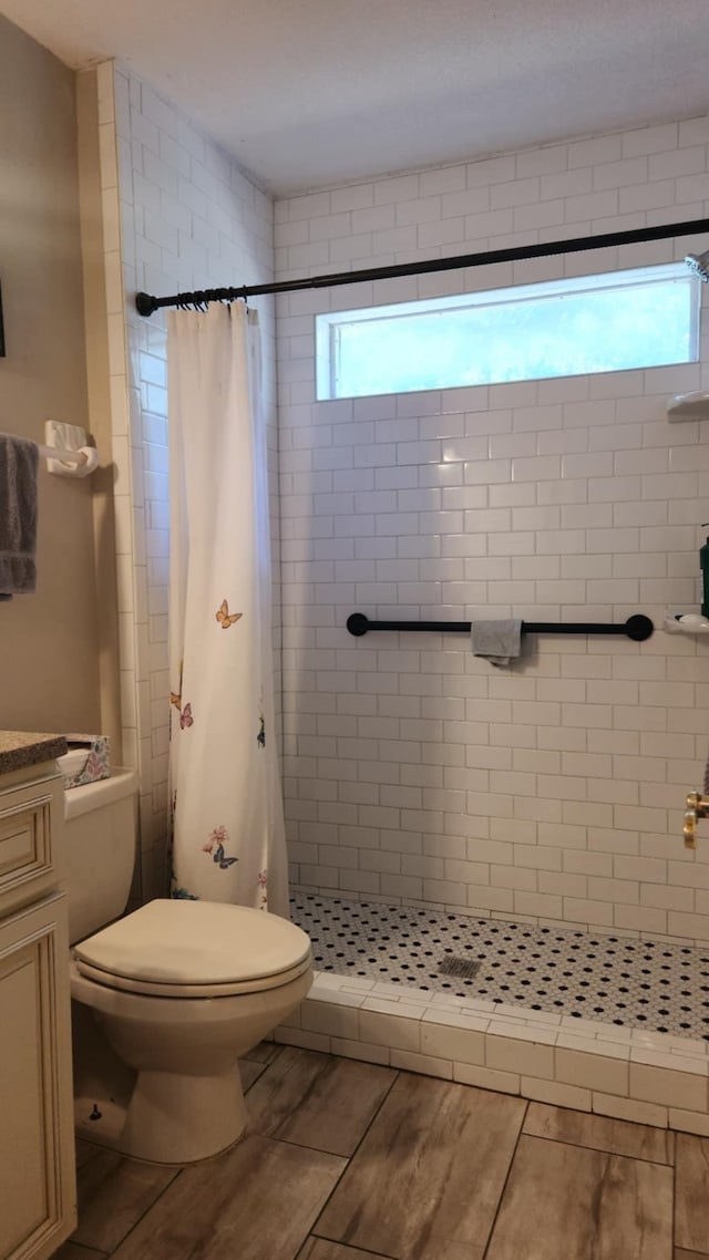 bathroom with a wealth of natural light, a shower stall, and toilet