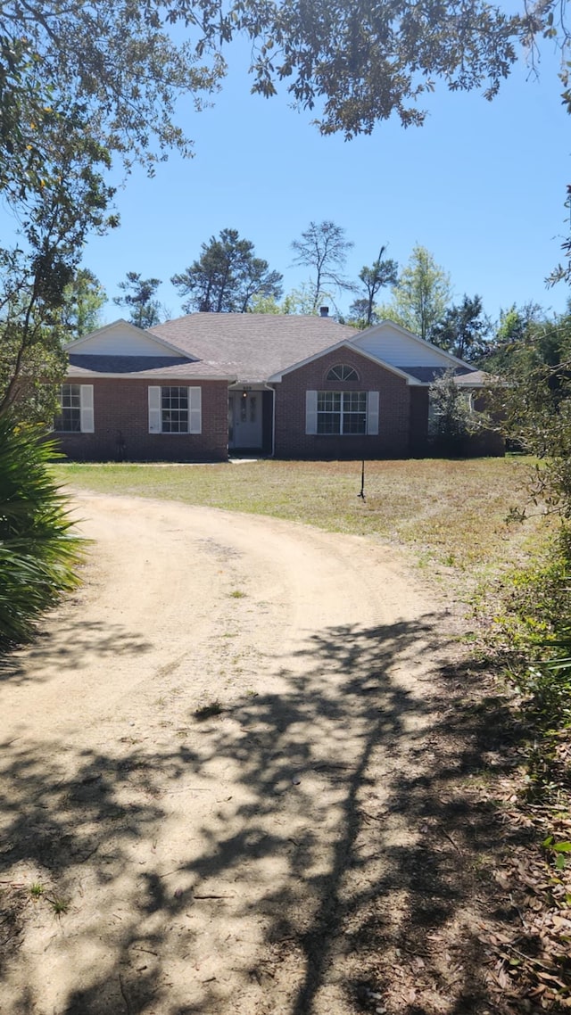 view of front of home featuring a front lawn and dirt driveway