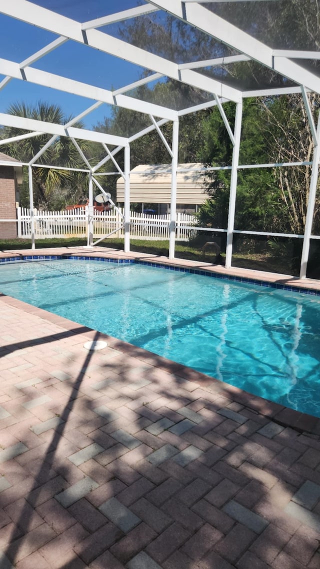 outdoor pool with a patio, fence, and a lanai