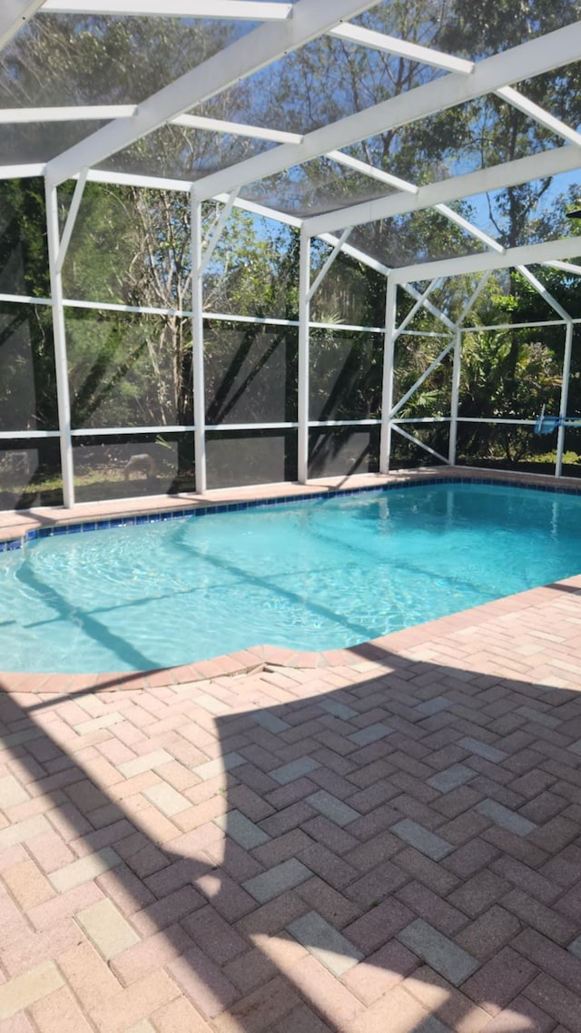 outdoor pool featuring glass enclosure and a patio area