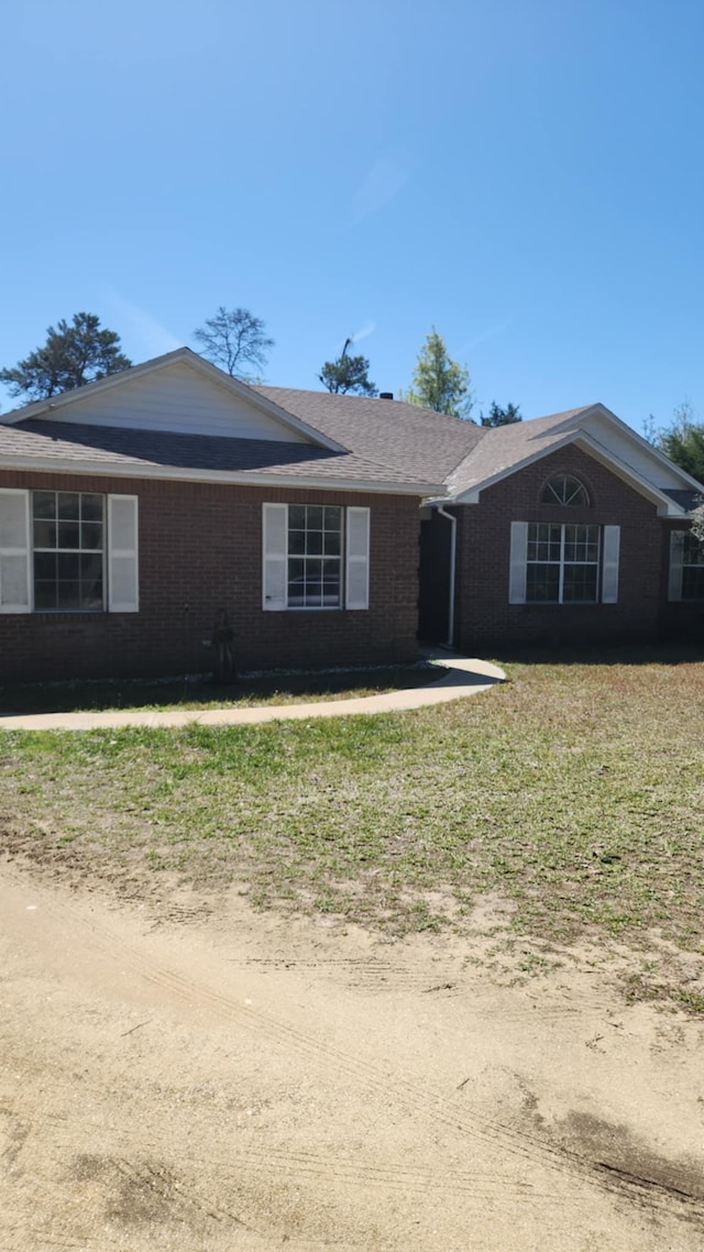 ranch-style home featuring brick siding and a front yard