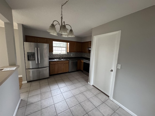 kitchen featuring appliances with stainless steel finishes, pendant lighting, tasteful backsplash, sink, and light tile patterned floors