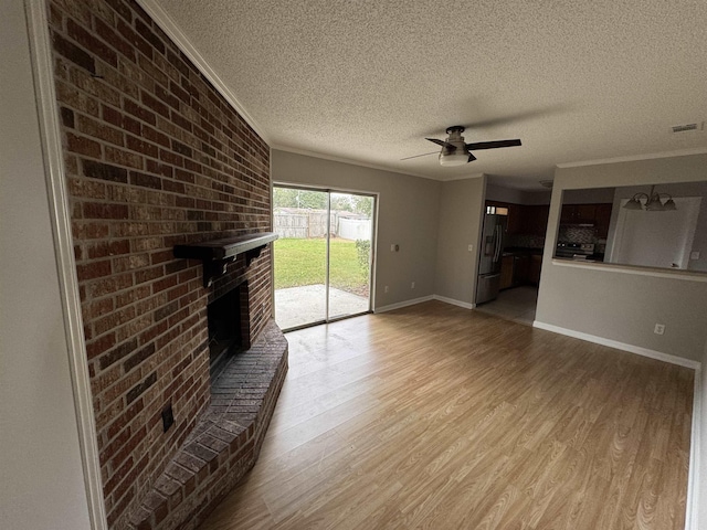 unfurnished living room with crown molding, light hardwood / wood-style flooring, a brick fireplace, a textured ceiling, and ceiling fan