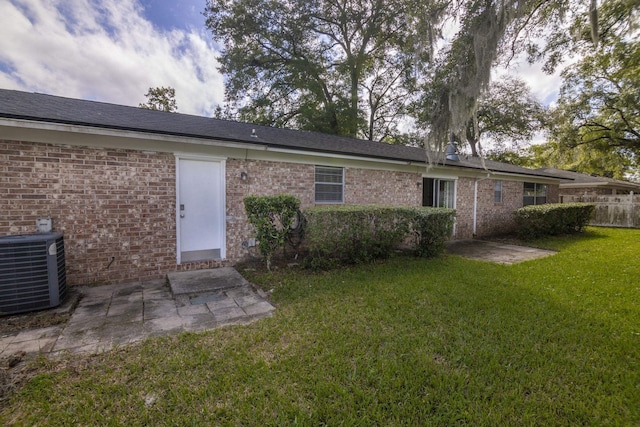 rear view of property featuring central AC and a lawn