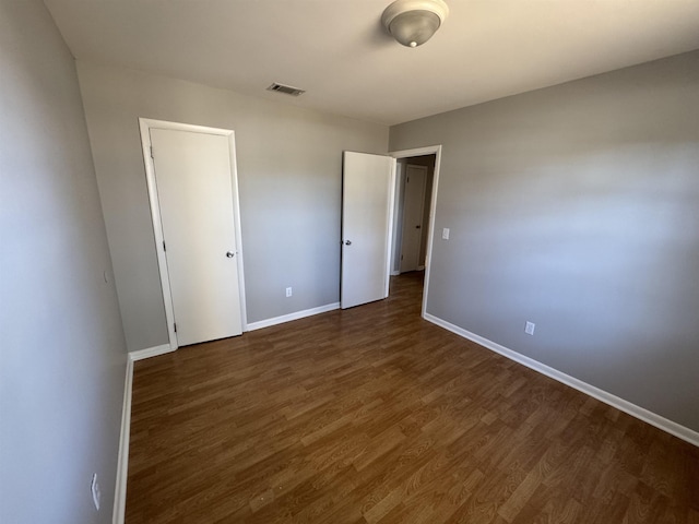 unfurnished bedroom with dark wood-type flooring and a closet