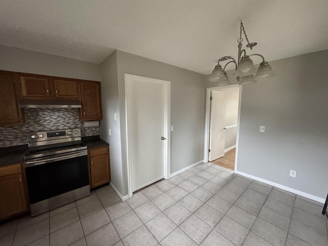 kitchen with stainless steel electric range oven, pendant lighting, backsplash, a chandelier, and light tile patterned floors