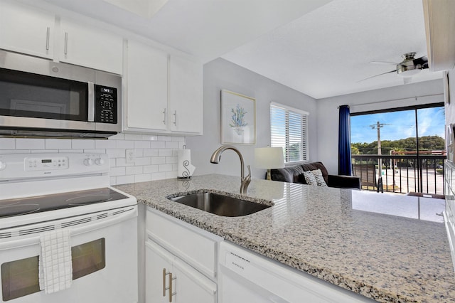 kitchen featuring white appliances, sink, tasteful backsplash, light stone counters, and white cabinetry