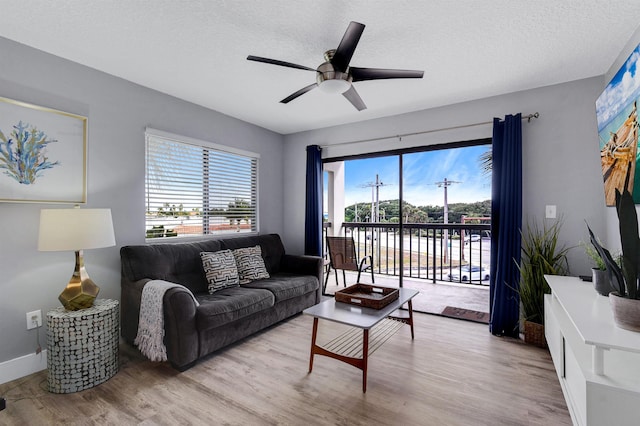 living room with plenty of natural light, light hardwood / wood-style floors, and ceiling fan