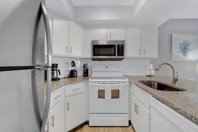 4250 A1A S B36, Saint Augustine, FL 32080 - kitchen featuring appliances with stainless steel finishes, tasteful backsplash, white cabinetry, light wood-style flooring, and light stone counters
