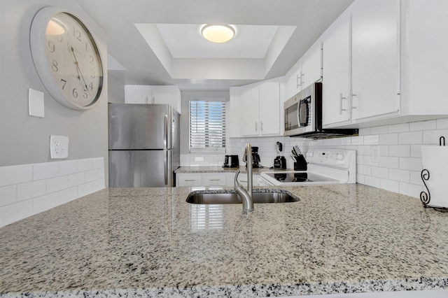 kitchen featuring light stone countertops, sink, a raised ceiling, white cabinets, and appliances with stainless steel finishes