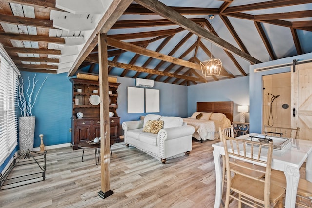 bedroom with lofted ceiling with beams, light hardwood / wood-style floors, and a barn door