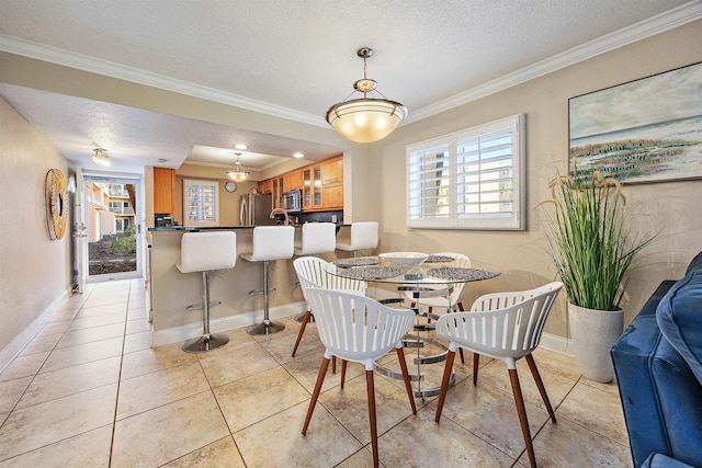 dining area featuring light tile patterned flooring, ornamental molding, and a textured ceiling