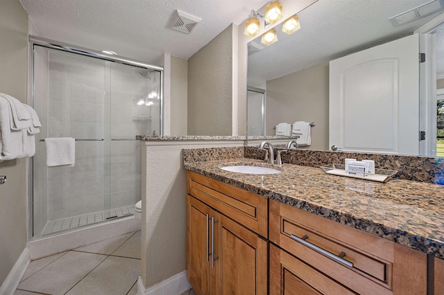 bathroom with tile patterned floors, vanity, an enclosed shower, and a textured ceiling