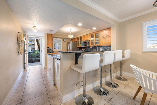 kitchen featuring stainless steel appliances, kitchen peninsula, plenty of natural light, a textured ceiling, and a breakfast bar