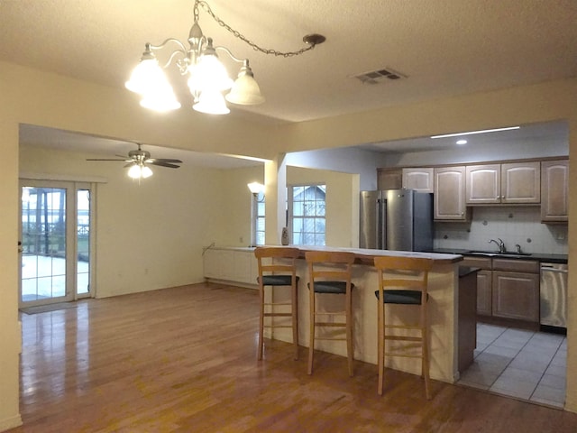 kitchen featuring dark countertops, open floor plan, a kitchen breakfast bar, stainless steel appliances, and pendant lighting