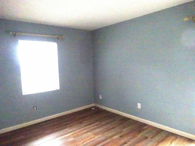 spare room featuring dark wood finished floors and baseboards