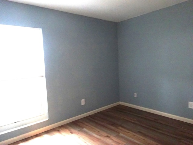 spare room with dark wood-type flooring and baseboards