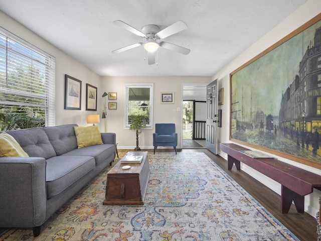 living area with plenty of natural light, wood finished floors, a ceiling fan, and baseboards
