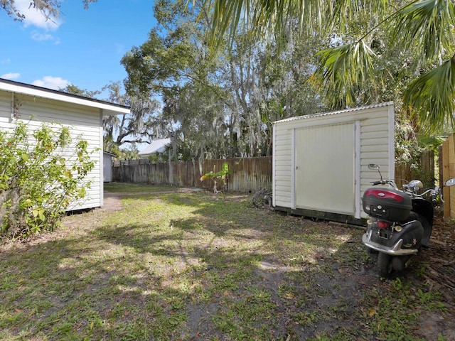 view of yard featuring fence, an outdoor structure, and a shed