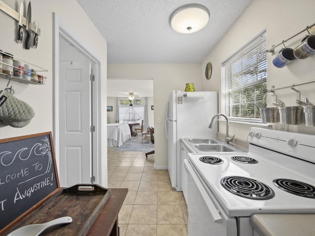 kitchen featuring light tile patterned floors, white appliances, a textured ceiling, and a sink