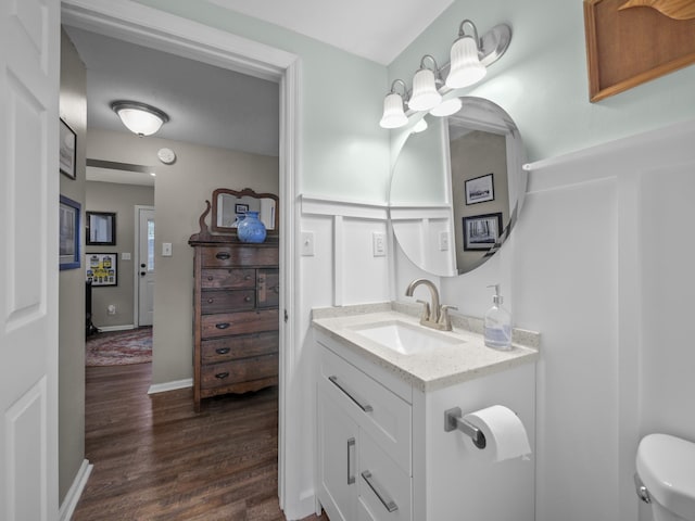 half bathroom with toilet, baseboards, wood finished floors, and vanity