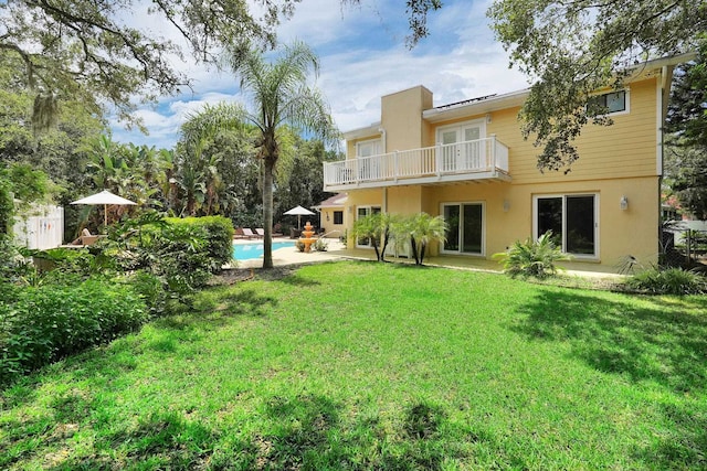 6 Versaggi Pl, Saint Augustine, FL 32080 - rear view of house featuring a balcony, a lawn, an outdoor pool, stucco siding, and a patio area