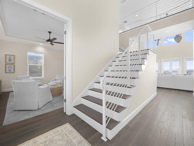 stairway with wood-type flooring, plenty of natural light, and ceiling fan