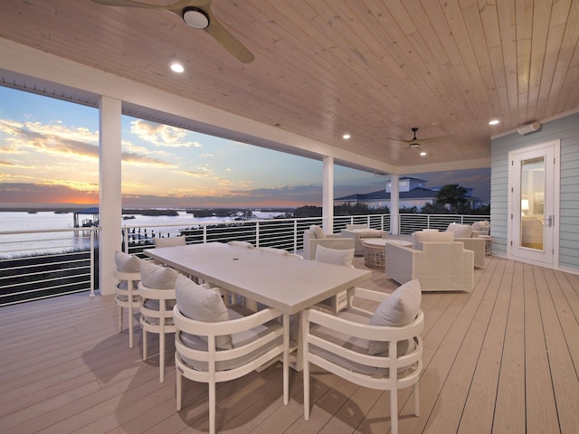 deck at dusk featuring ceiling fan, a water view, and an outdoor living space