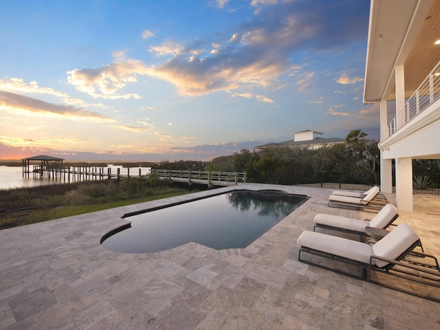 pool at dusk featuring a patio area and a water view